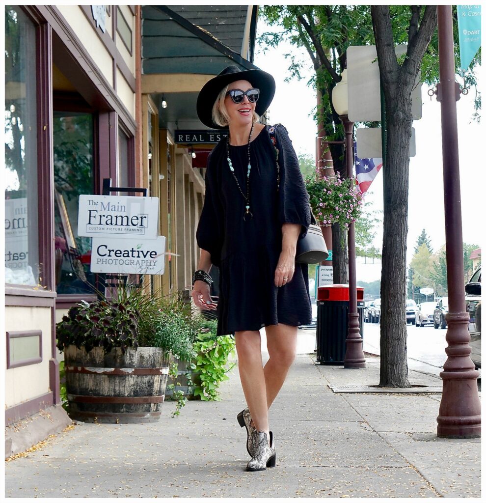 Sheree Frede of the SheShe Show standing in front of wood door wearing a knee length black dress