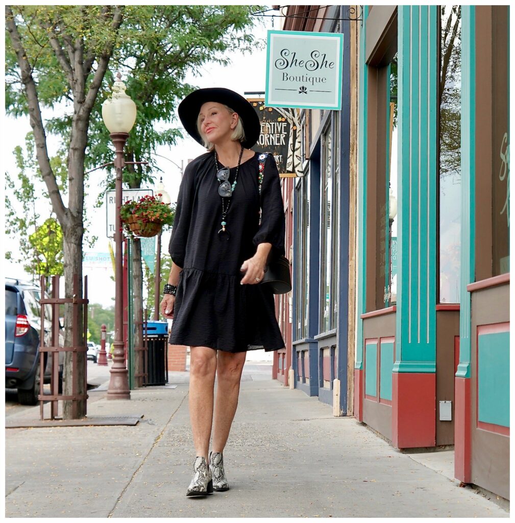 Sheree Frede of the SheShe Show standing in front of wood door wearing a knee length black dress