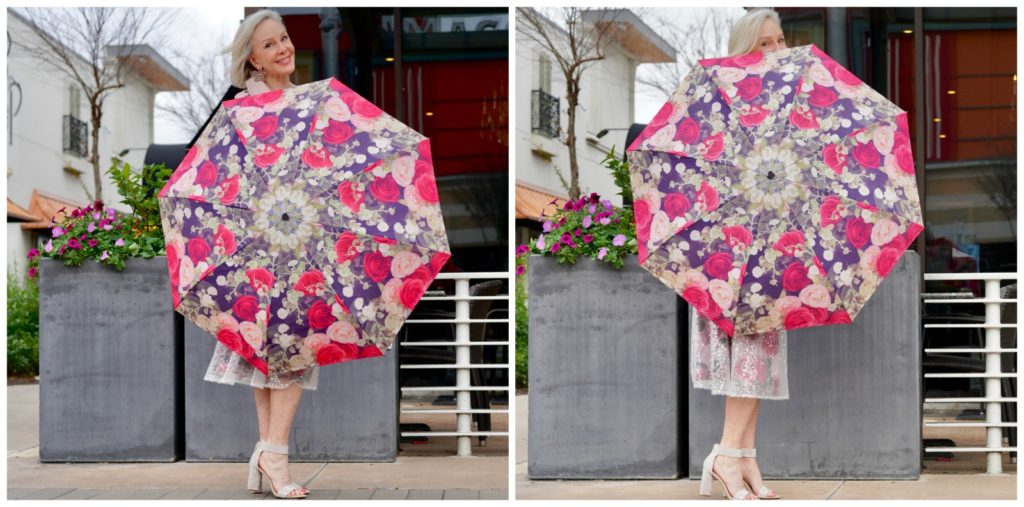 Sheree Frede standing in front of pretty spring flowers wearing a pink floral skirt and blush leather jacket and pink floral umbrella