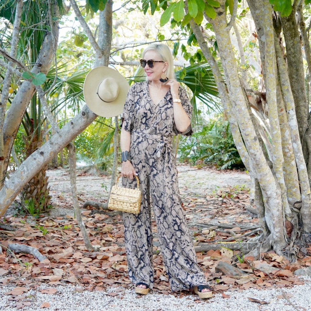 snakeskin print jumpsuit, bamboo bag, black wedge sandals, sunglasses, tropical setting