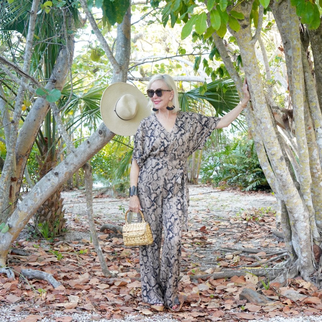 snakeskin print jumpsuit, bamboo bag, black wedge sandals, sunglasses, tropical setting