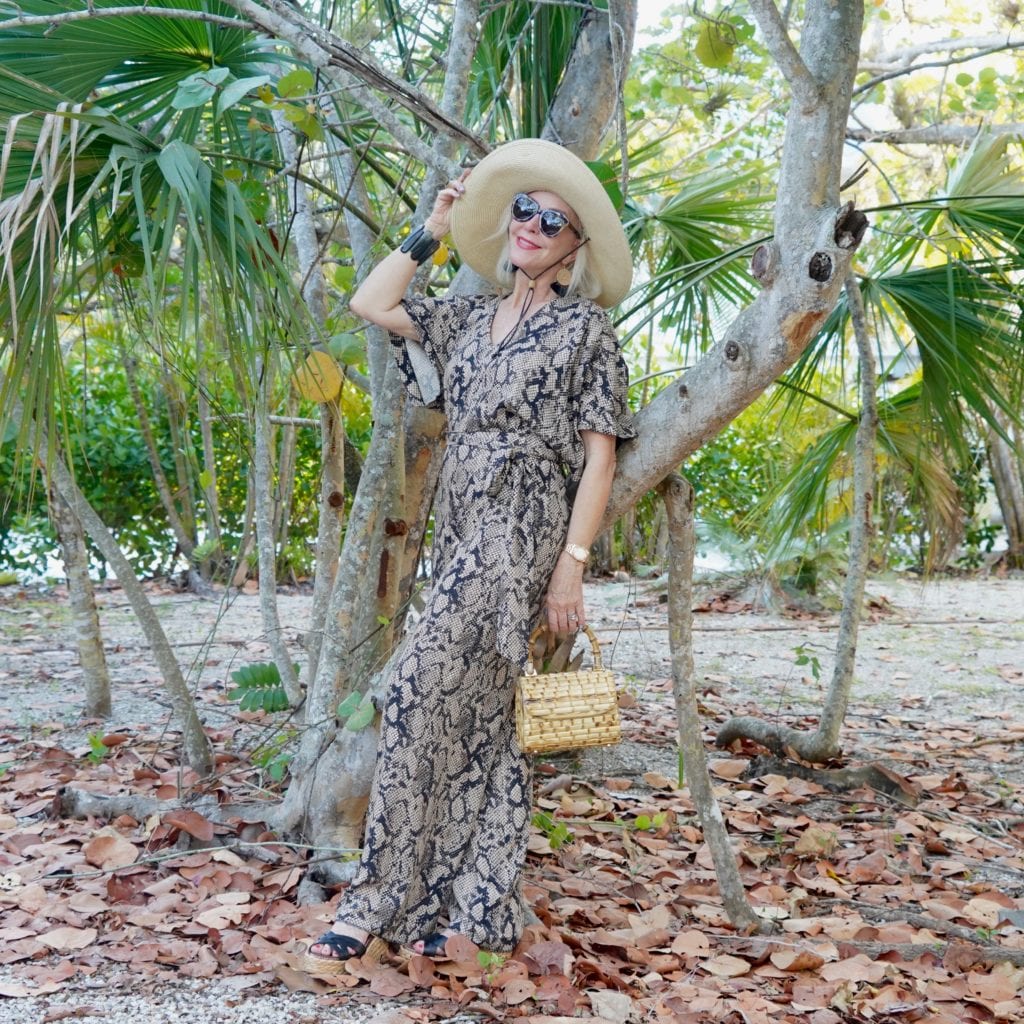 snakeskin print jumpsuit, bamboo bag, black wedge sandals, sunglasses, tropical setting