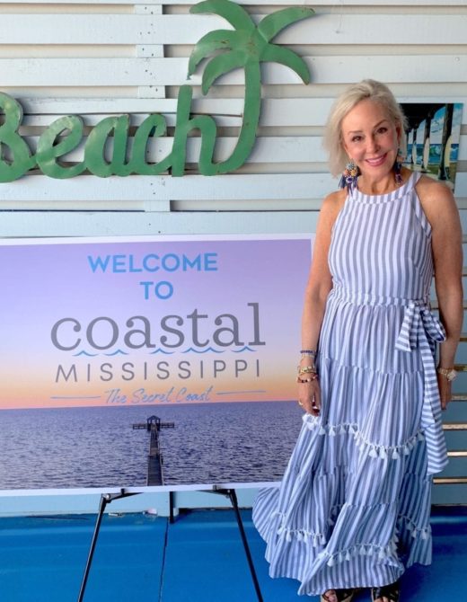 Sheree Frede of the SheShe Show wearing a blue dress by Coastal Mississippe sign