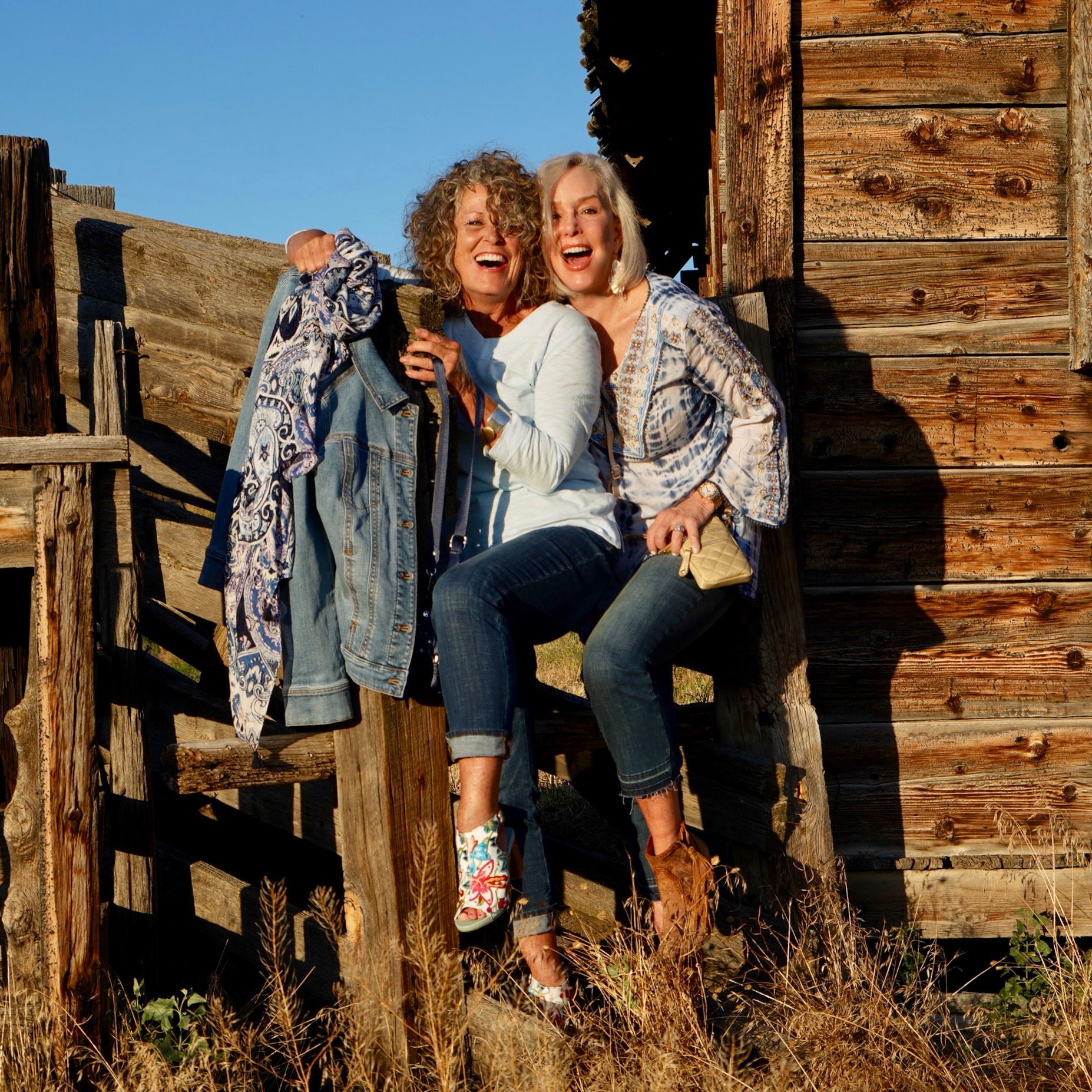 Ruthie and Sheree wearing jeans by a wood fence