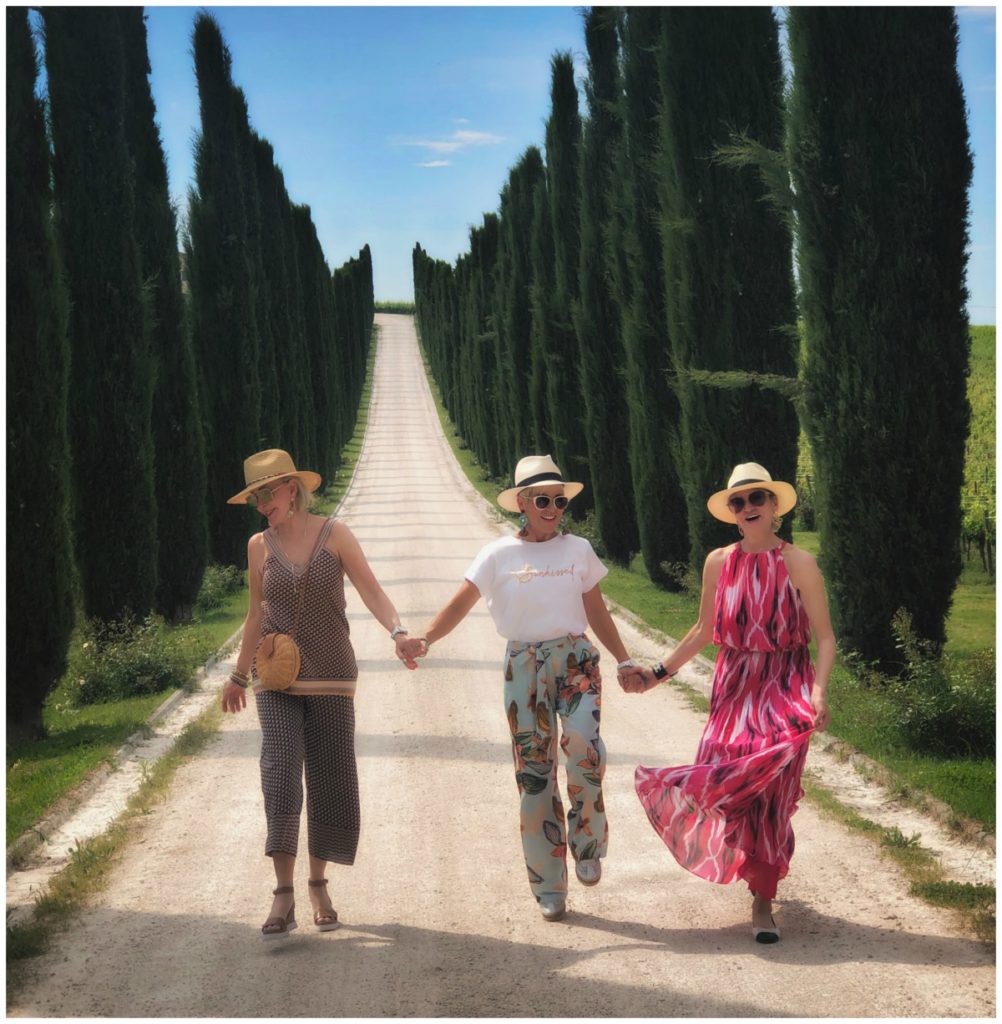 Sheree, Shauna, and Jamie holding hands walking down a road lined with Italian Cypress