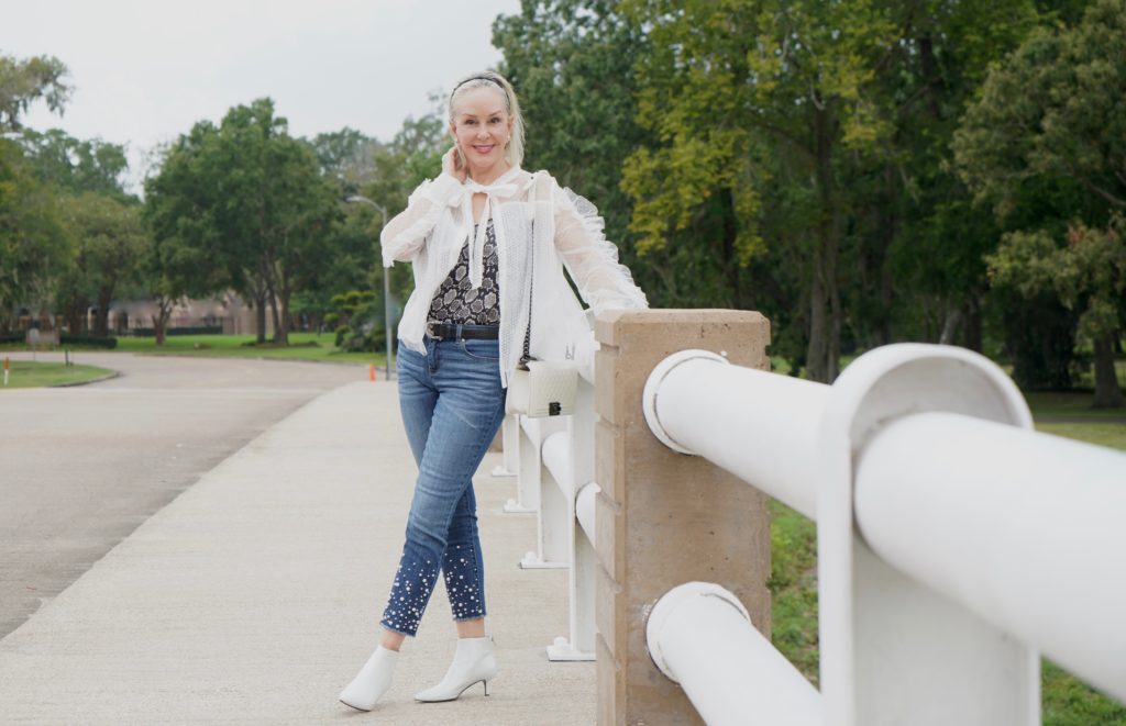 sheshe of the SheShe Show wearing white mesh and ruffle top over skinny crop jeans with pealrs