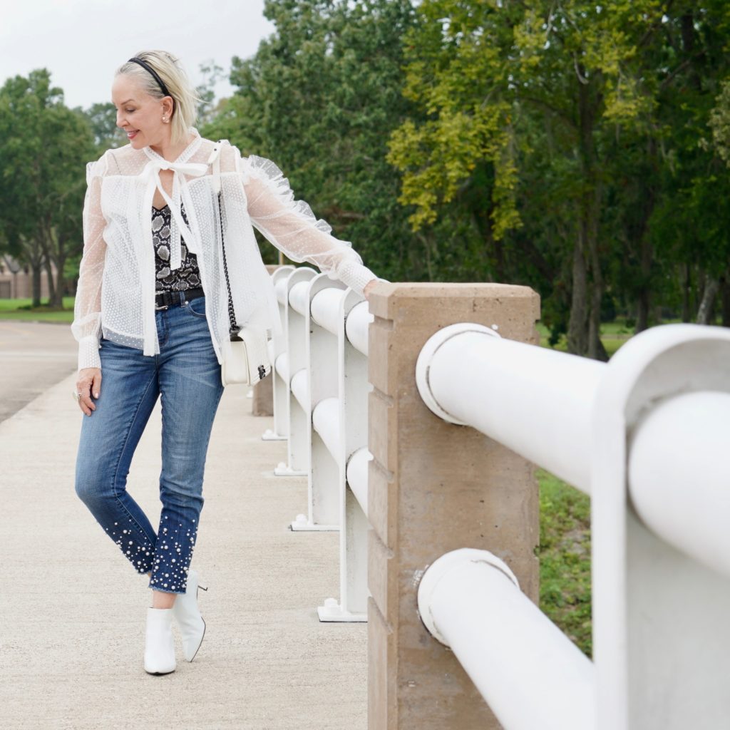 sheshe of the SheShe Show wearing white mesh and ruffle top over skinny crop jeans with pealrs