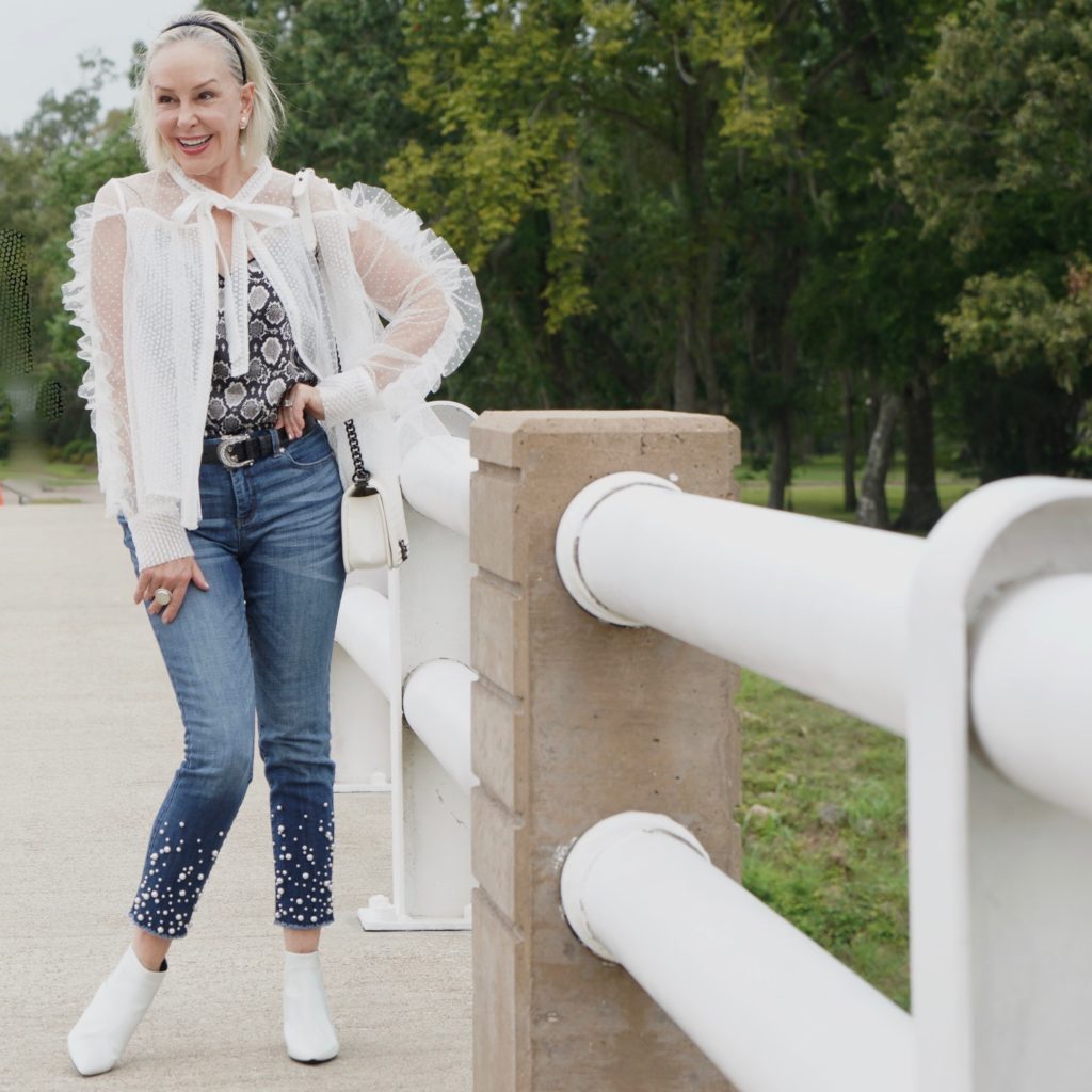 sheshe of the SheShe Show wearing white mesh and ruffle top over skinny crop jeans with pealrs