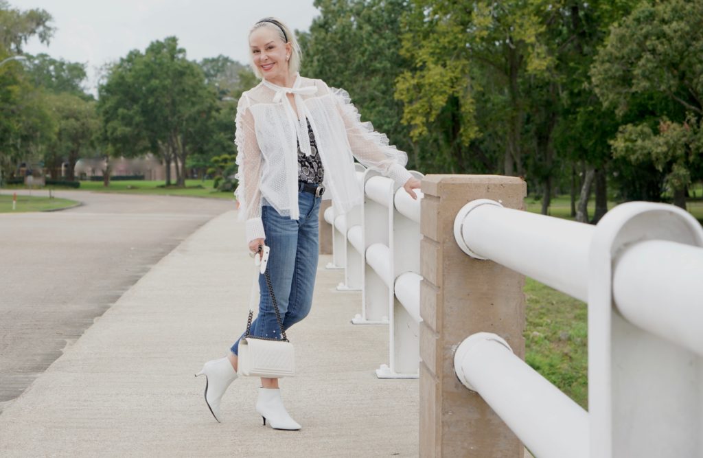 sheshe of the SheShe Show wearing white mesh and ruffle top over skinny crop jeans with pealrs