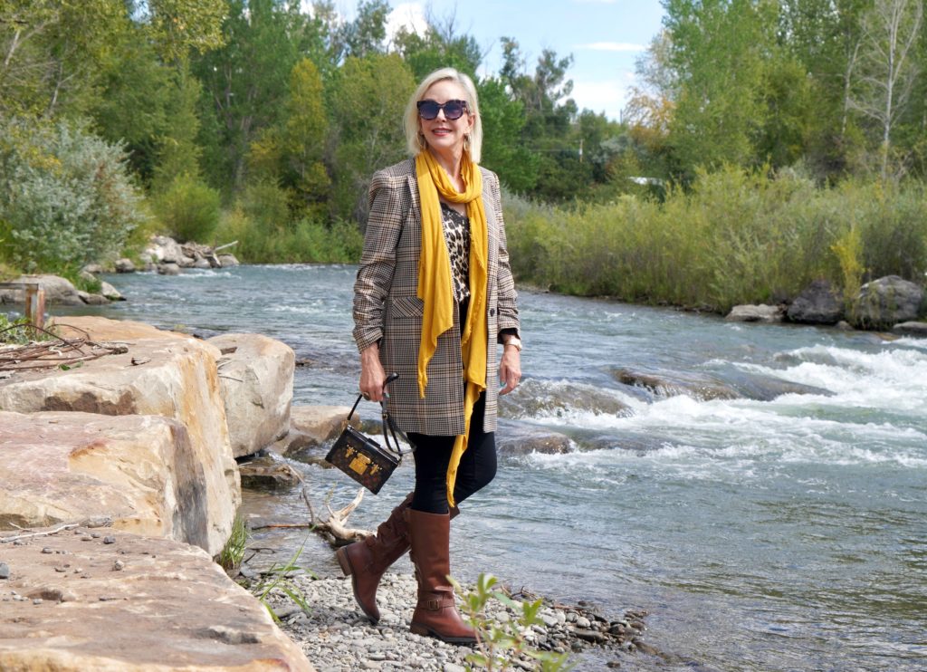 SheShe Show in plaid blazert over black jeans and brown boots walk ing the river