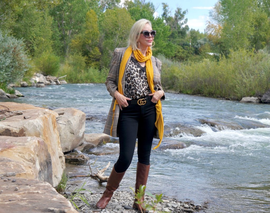 SheShe Show in plaid blazert over black jeans and brown boots walk ing the river