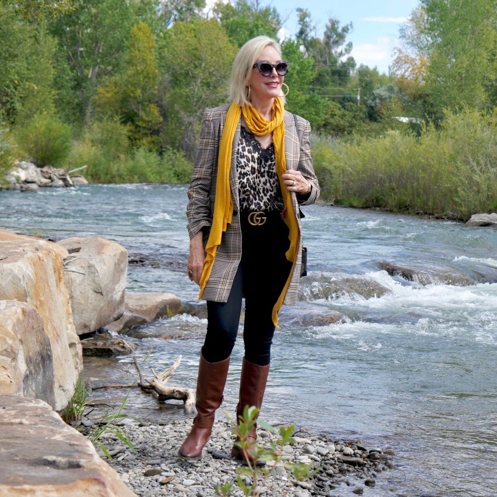 SheShe Show in plaid blazert over black jeans and brown boots walk ing the river