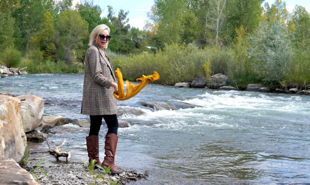 SheShe Show in plaid blazert over black jeans and brown boots walk ing the river