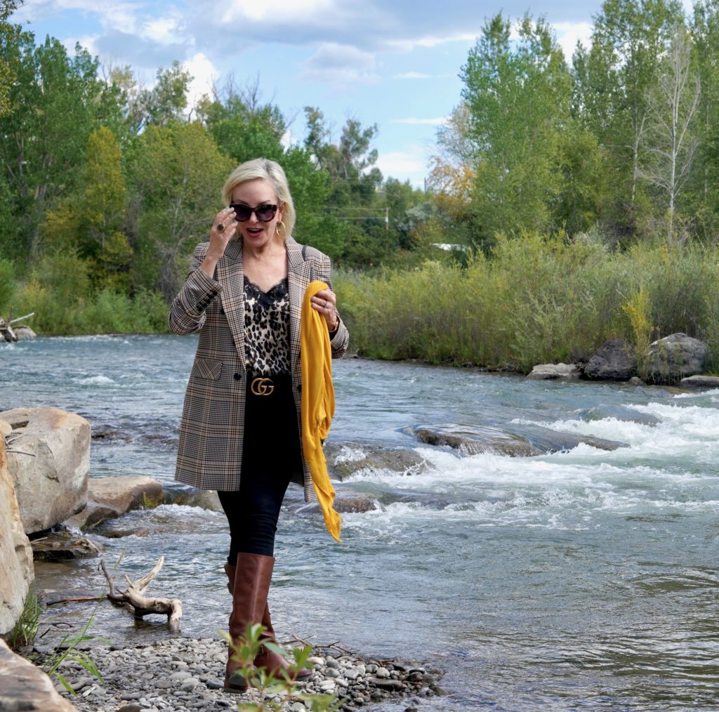 SheShe Show in plaid blazert over black jeans and brown boots walk ing the river