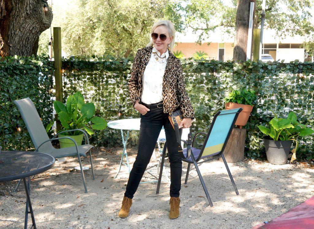 Sheree of the SheShe Show wearing Chico's leopard moto jacket over ivory ruffle blouse and black jeans with tan suede booties