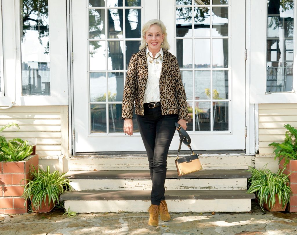 Sheree of the SheShe Show wearing Chico's leopard moto jacket over ivory ruffle blouse and black jeans with tan suede booties