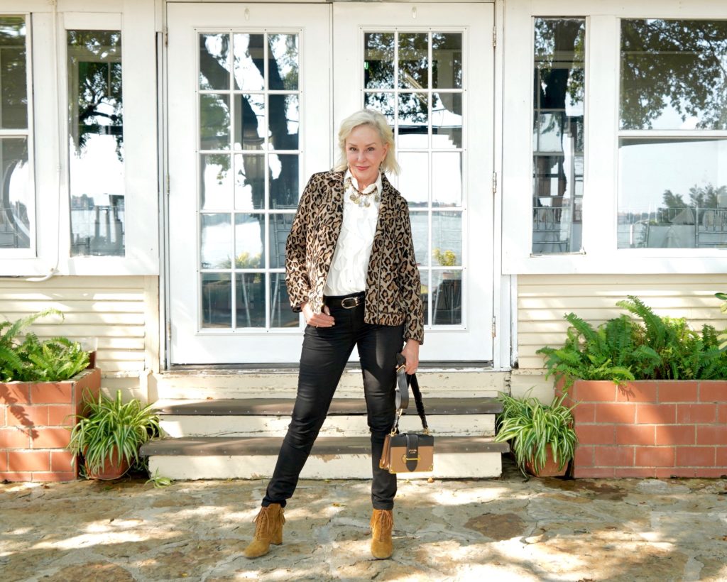 Sheree of the SheShe Show wearing Chico's leopard moto jacket over ivory ruffle blouse and black jeans with tan suede booties