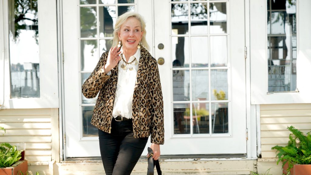 Sheree of the SheShe Show wearing Chico's leopard moto jacket over ivory ruffle blouse and black jeans with tan suede booties