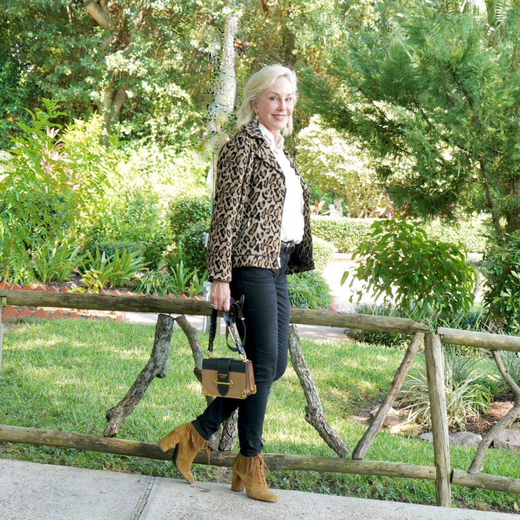 Sheree of the SheShe Show wearing Chico's leopard moto jacket over ivory ruffle blouse and black jeans with tan suede booties