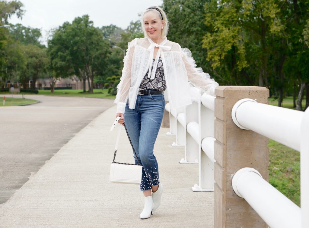 sheshe of the SheShe Show wearing white mesh and ruffle top over skinny crop jeans with pealrs