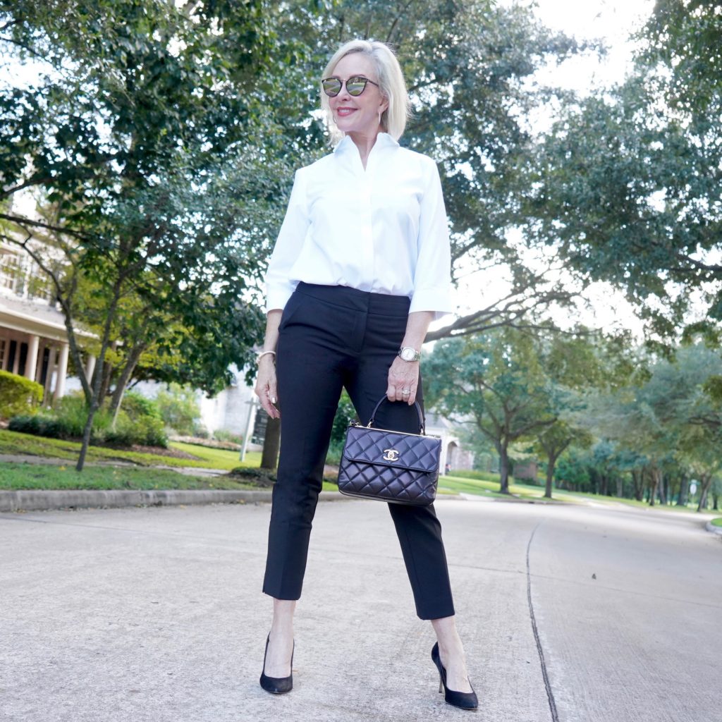 Sheree of the SheShe Show wearing basic black pants and white shirt with black pumps and Chanel bag