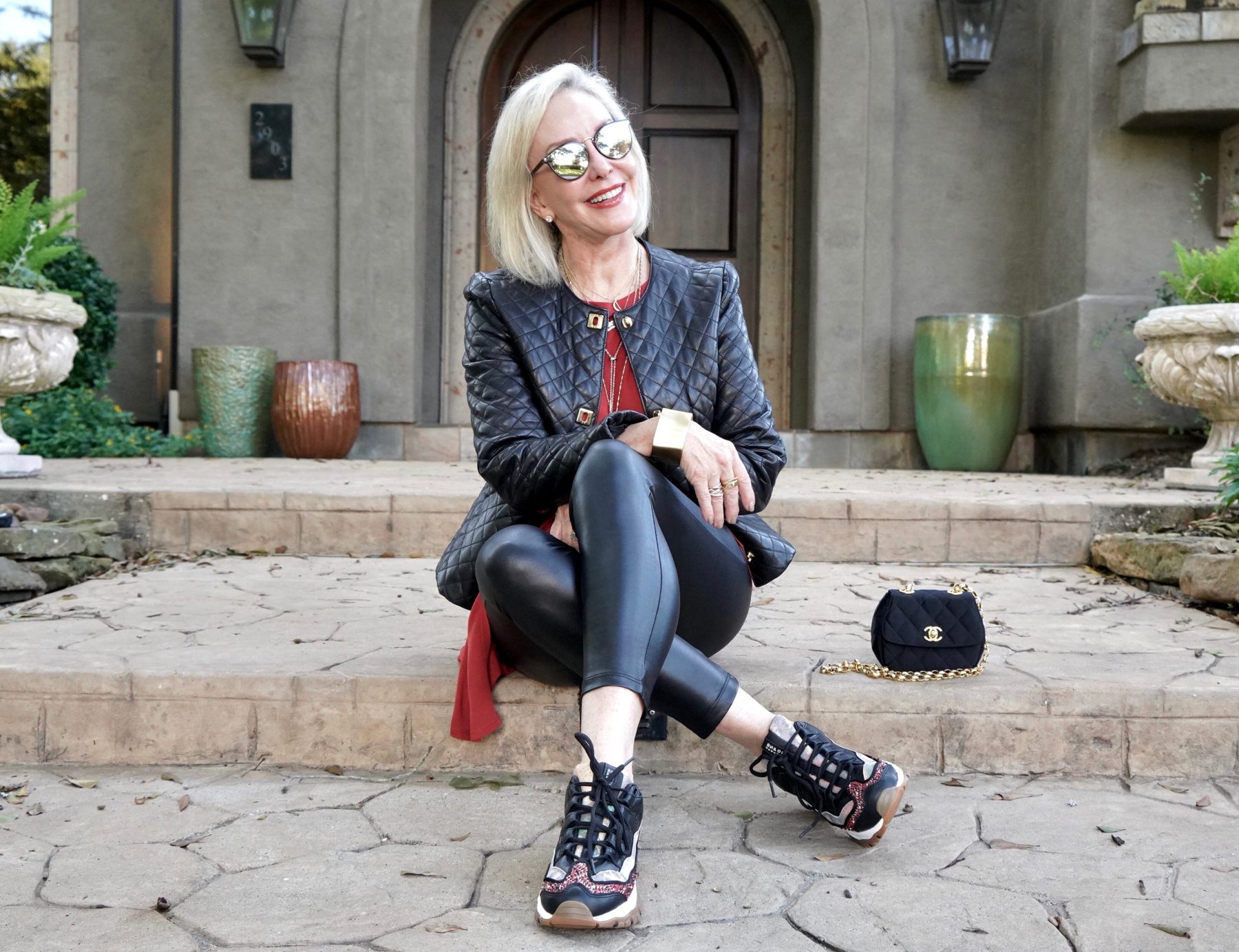 Sheree of the SheShe Show wearing a black moto jacket over faux leather leggings and black sneakers