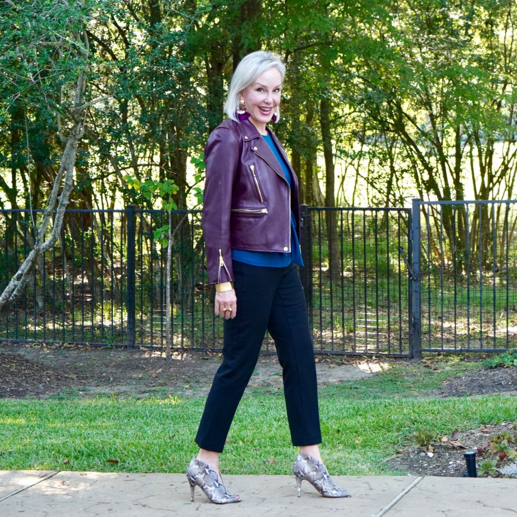 Sheree of the SheShe Show wearing a burgundy leather moto jacket over classic black pants and snakeskin booties