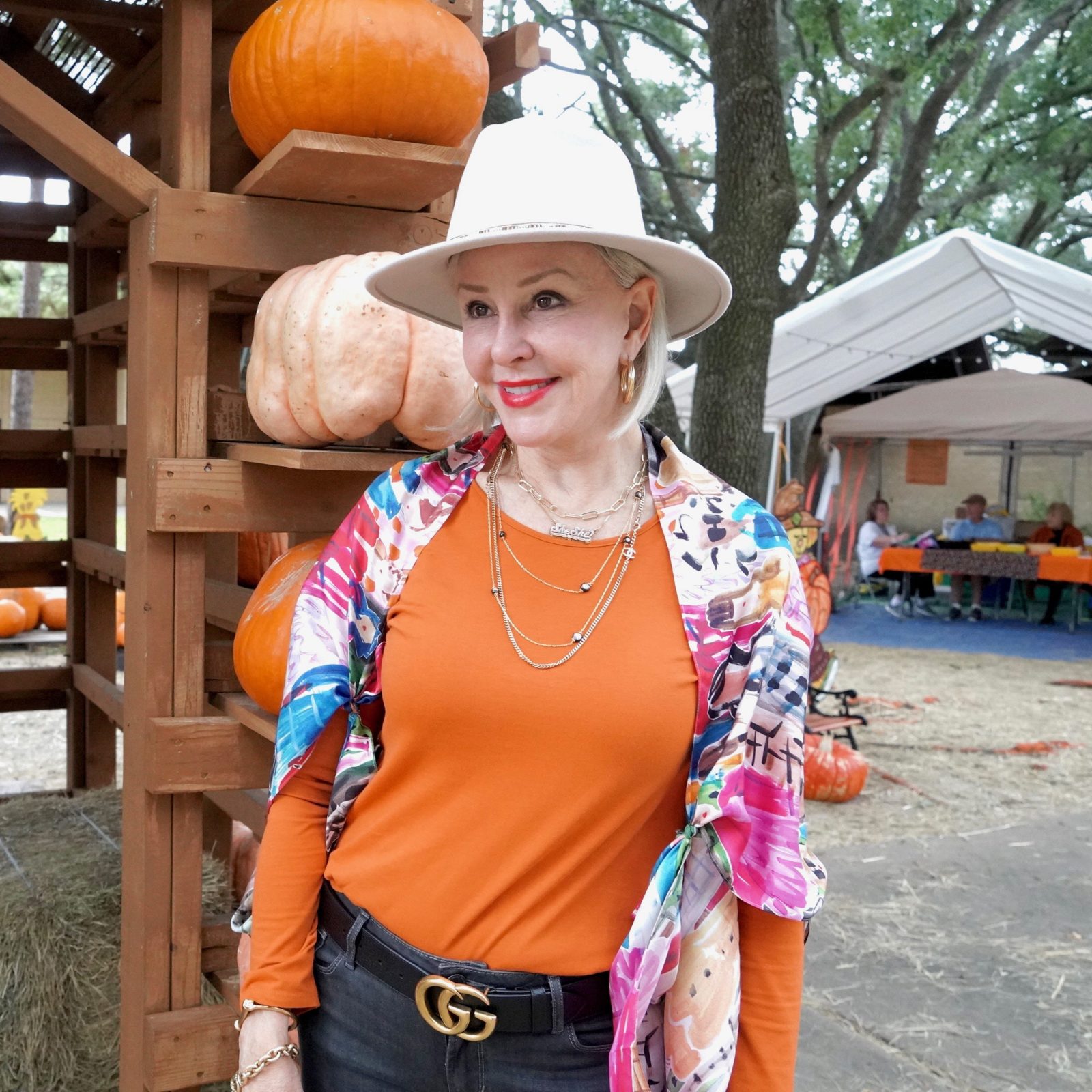Sheree Frede of the SheShe Show weqring orange top with colorful scarf as a wrap and off white hat