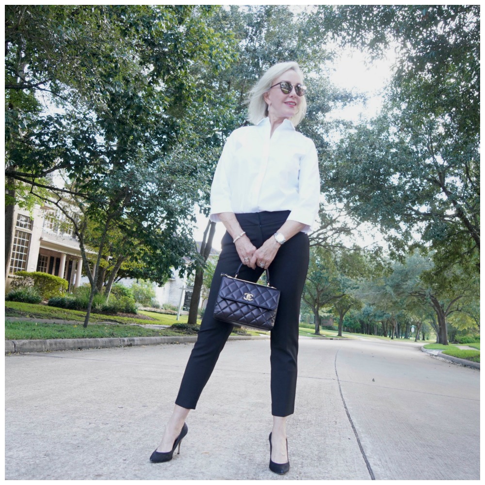 Sheree of the SheShe Show wearing basic black pants and white shirt with black pumps and Chanel bag