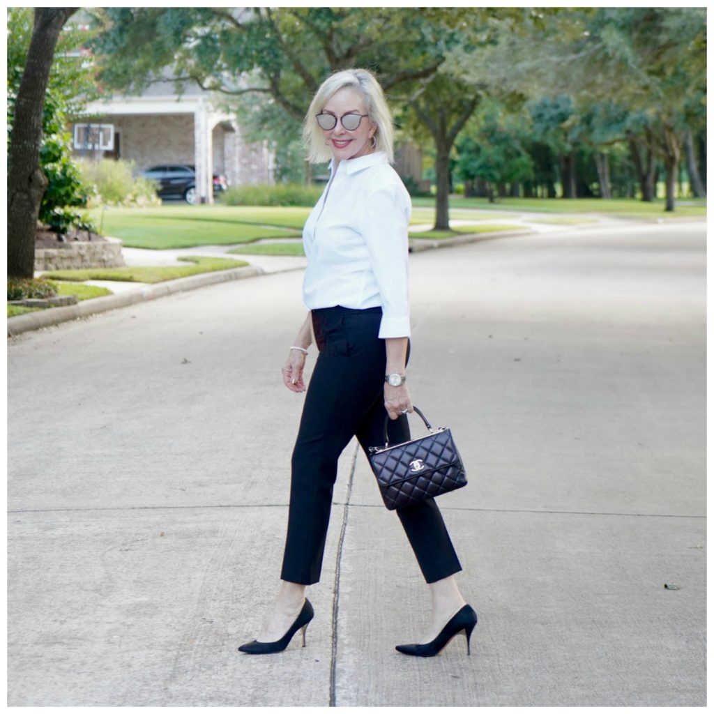 Sheree of the SheShe Show wearing basic black pants and white shirt with black pumps and Chanel bag