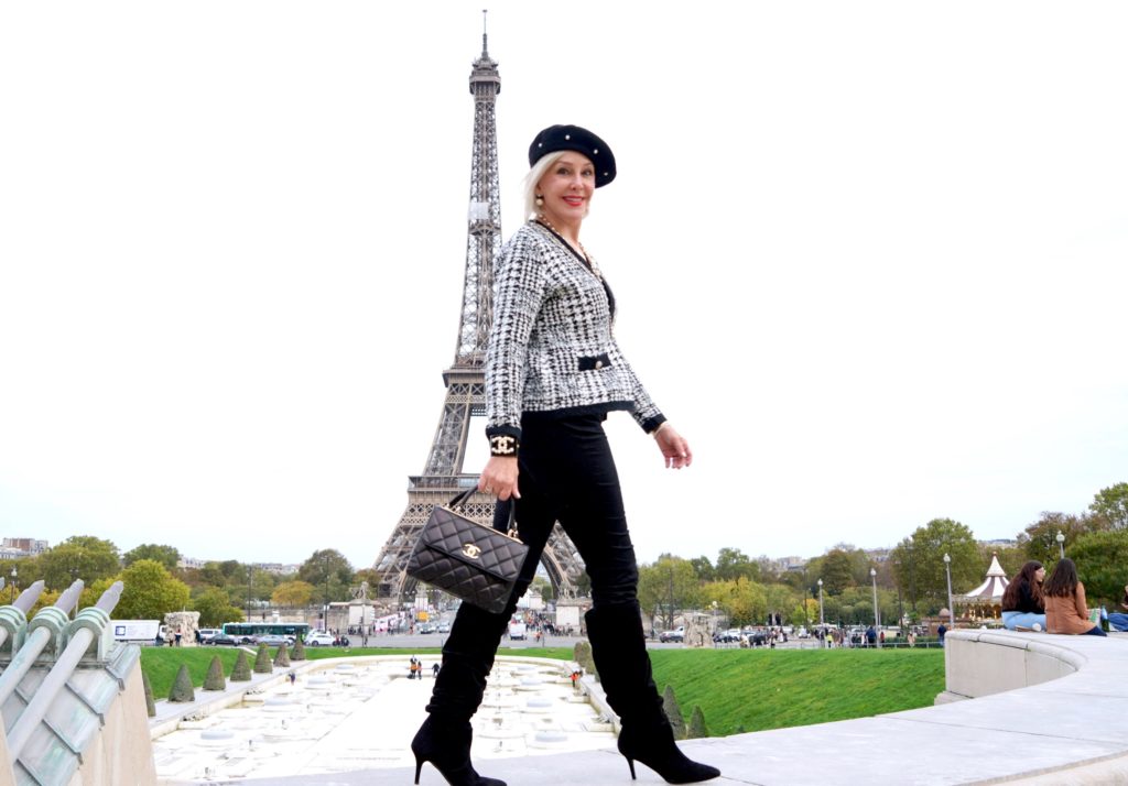 Sheree Frede of the SheShe Show walking and wearing black pants and black and whit knit jacket and beret.