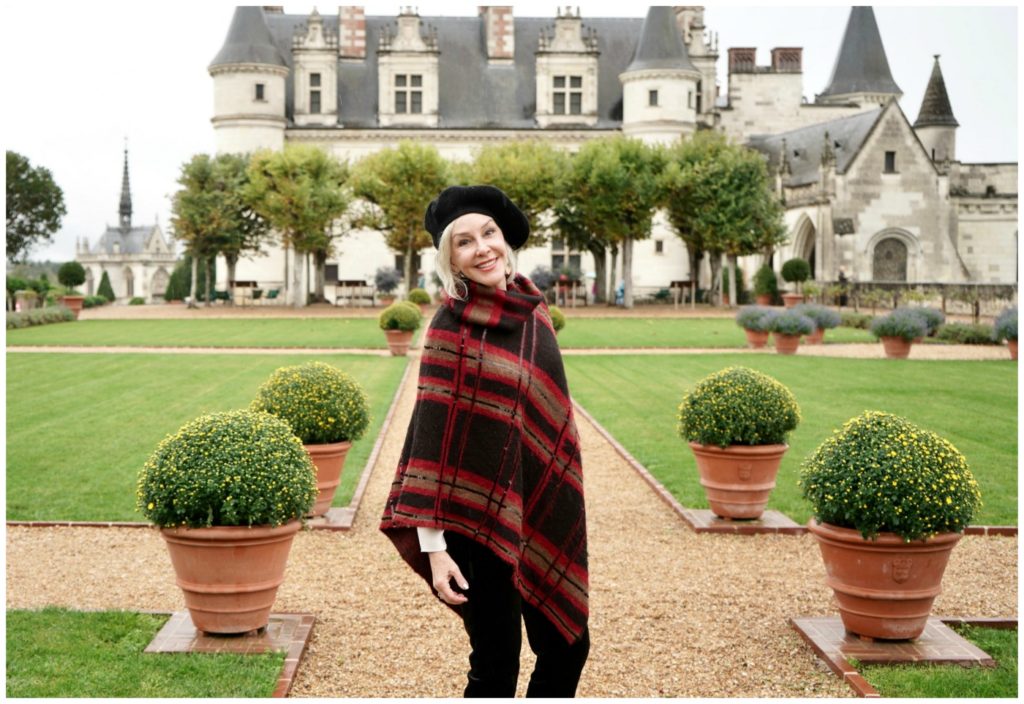 Sheree of the SheShe Show standing in front of big castle wearing a knit poncho and black beret