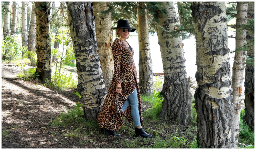 SheShe of the SheShe Show wearing a leopard wrap dress walking through  large aspen trees