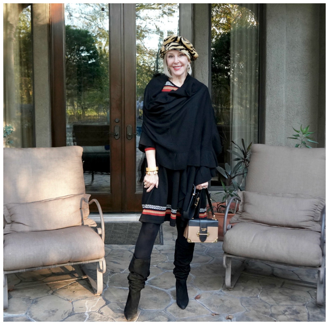 Sheree of the SheShe Show wearing a black wrap over a sweater dress and hat