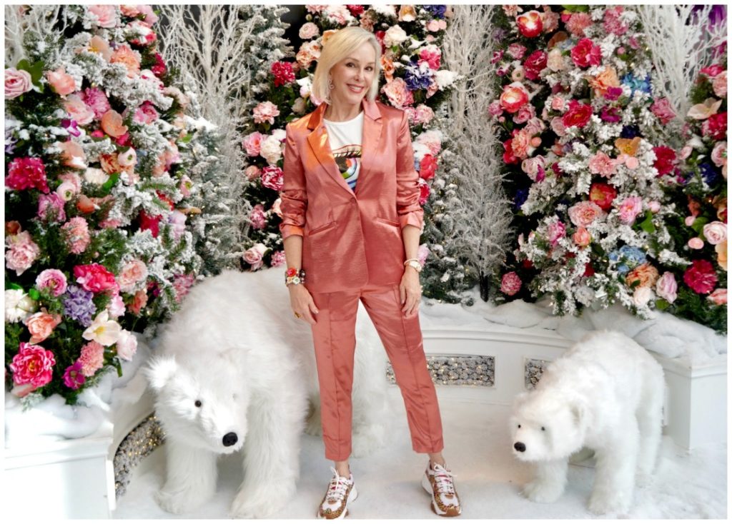 Sheree of the SheSheShow standing in front of pink and coral flowers and 2 stuffed polar bears