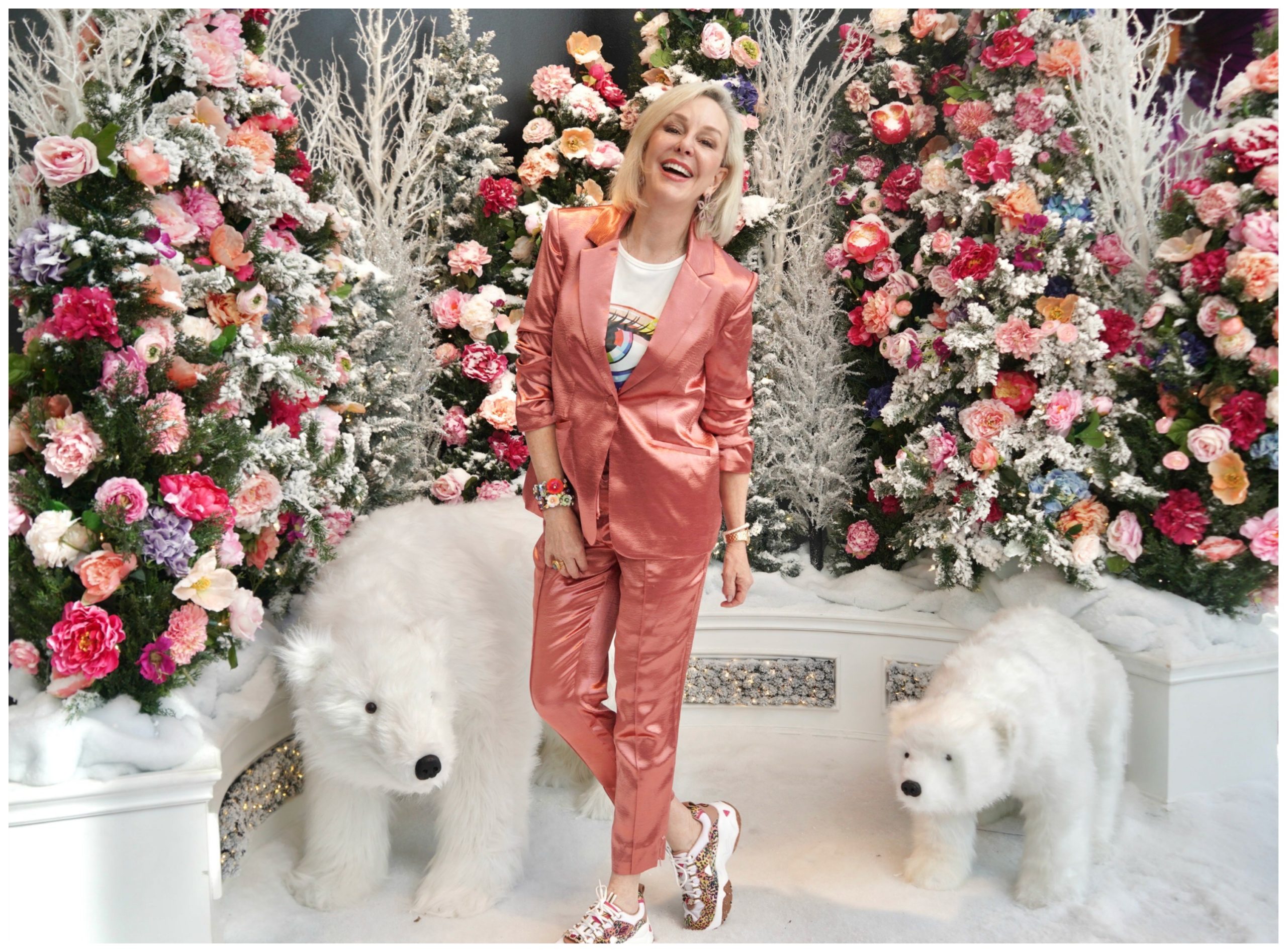 Sheree of the SheSheShow standing in front of pink and coral flowers and 2 stuffed polar bears
