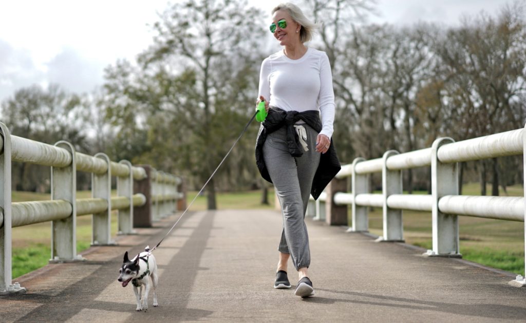 sheree Frede of the SheShe Show walking dog across a bridge wearing athleisure