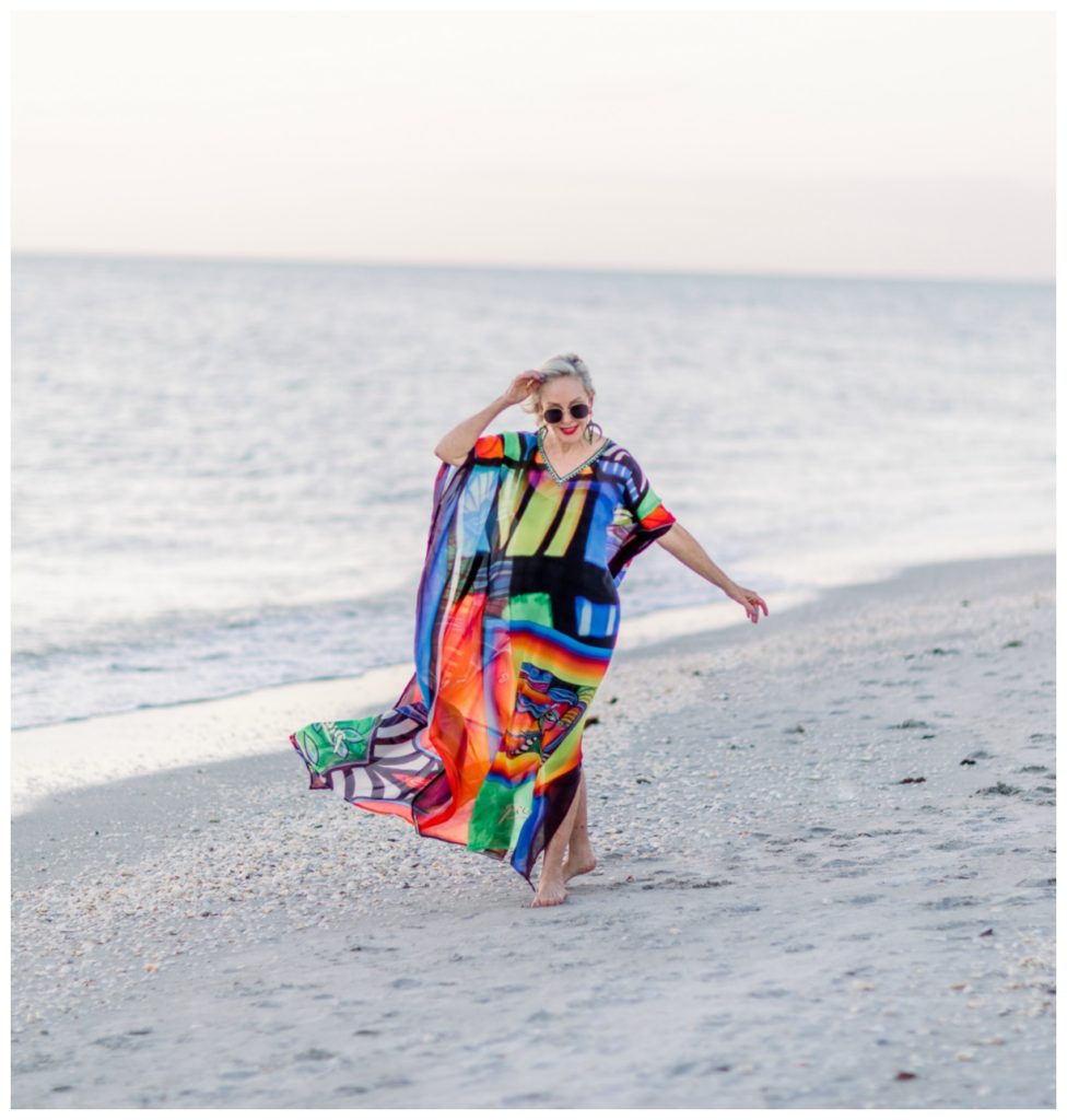 Sheree of the SheShe Show on the beach wearing an abstract multi colored kaftan