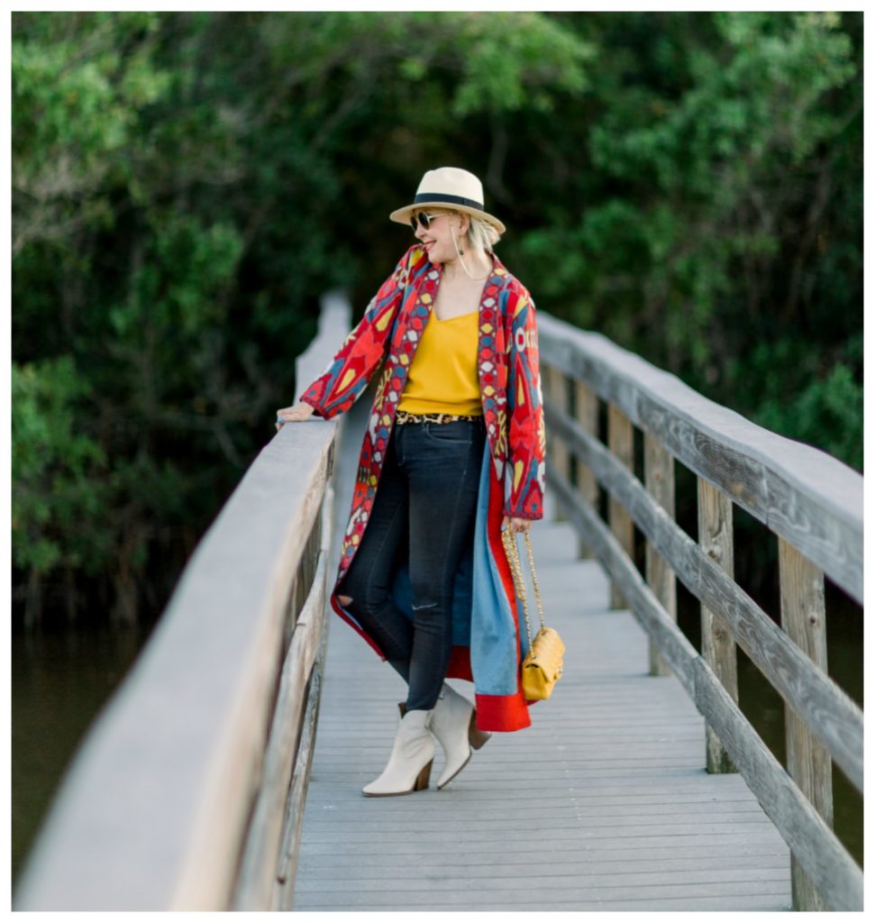 Sheree Frede of the SheShe Show on wooden bridge wearing jeans and a duster