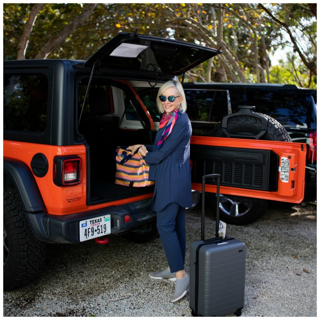 Sheree of the SheShe SHow loading suitcase and tote bag wearing Nic + Zoë Tech Stretch pants tank and jacket