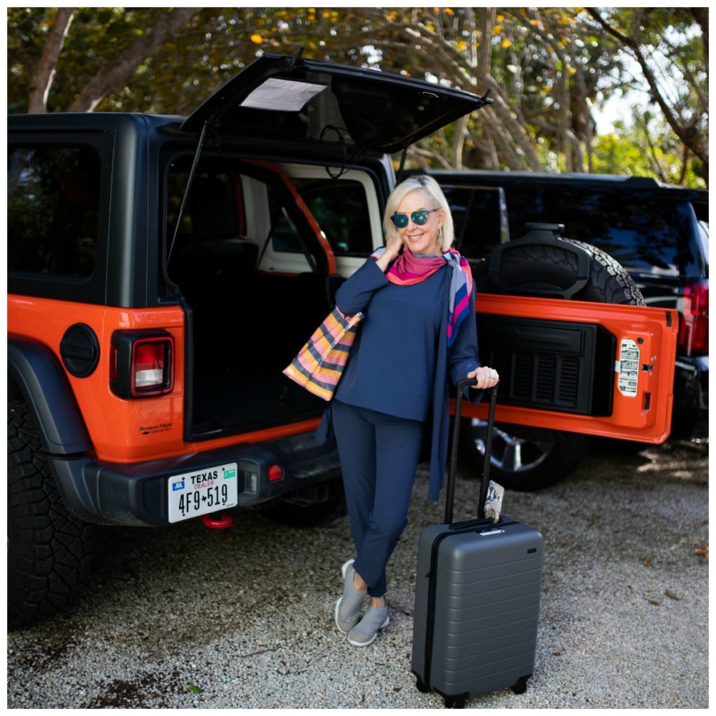 Sheree of the SheShe SHow loading suitcase and tote bag wearing Nic + Zoë Tech Stretch pants tank and jacket