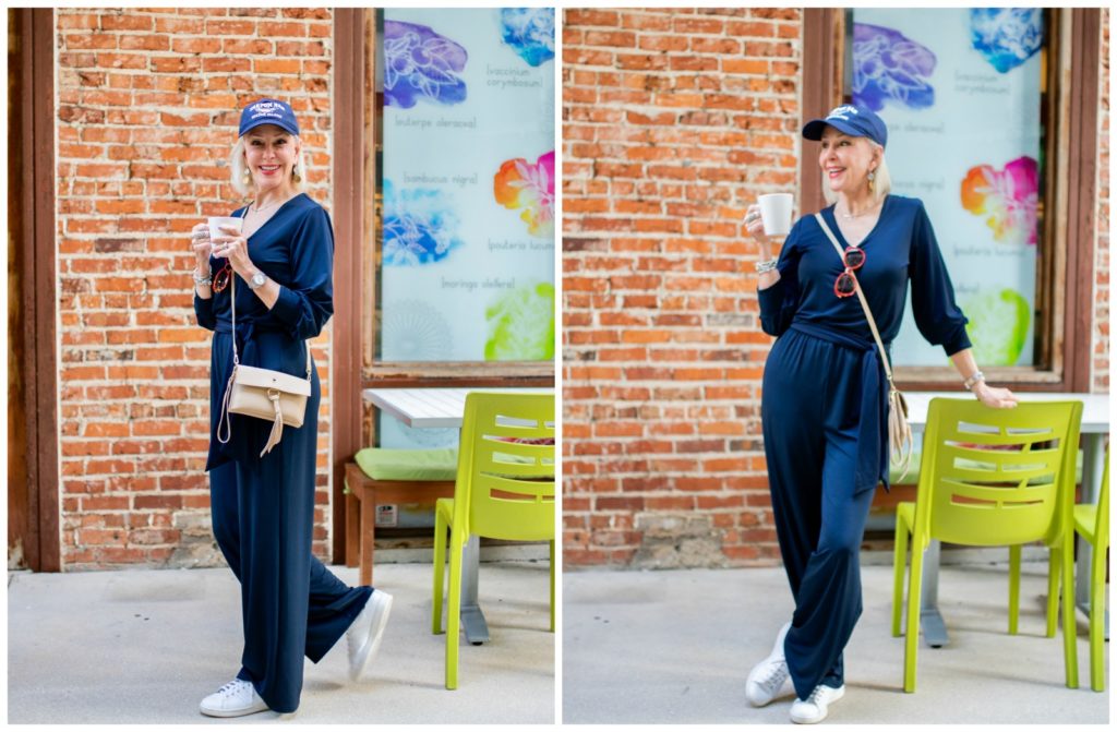 Sheree Frede of the SheSheShow in outdoor courtyeard wearing a simple navy jumpsuit and baseball cap