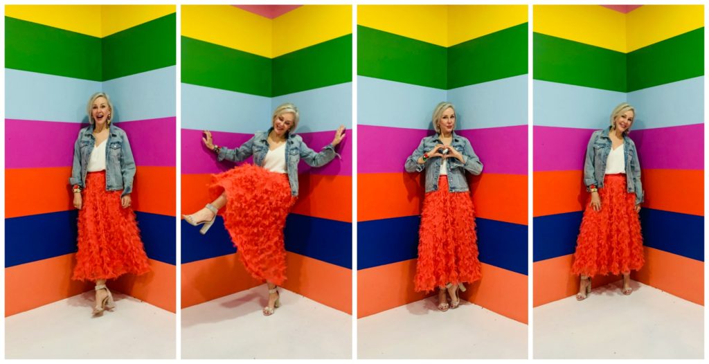 Sheree Frede of the SheShe Show wearing a bright coral midi length skirt, denim jacket over white camisole and rhinestone shoes