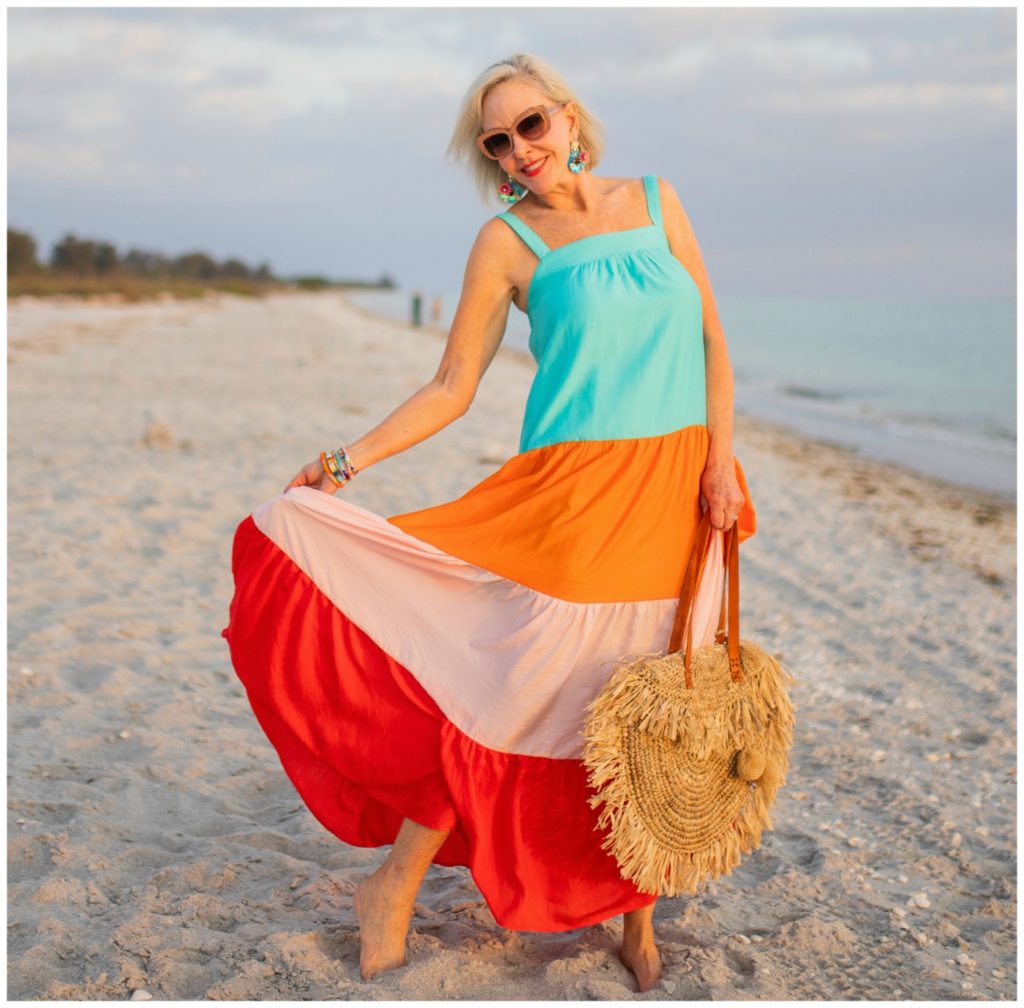 Sheree Frede of the SheShe Show on the beach at sunset wearing a orange and turquoise maxi dress