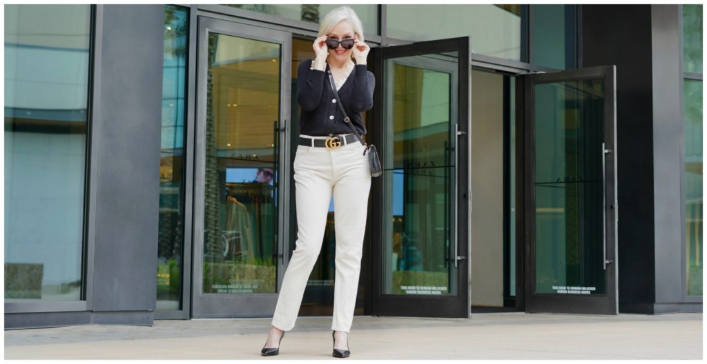 Sheree Frede of the SheShe Show standing in front of a store front wearing off white jeans and black sweater. 