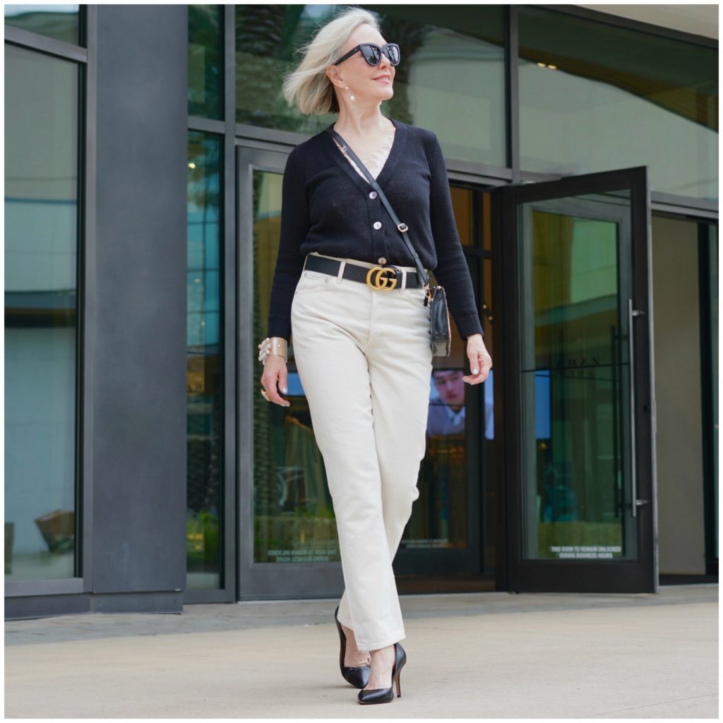 Sheree Frede of the SheShe Show standing in front of a store front wearing off white jeans and black sweater.