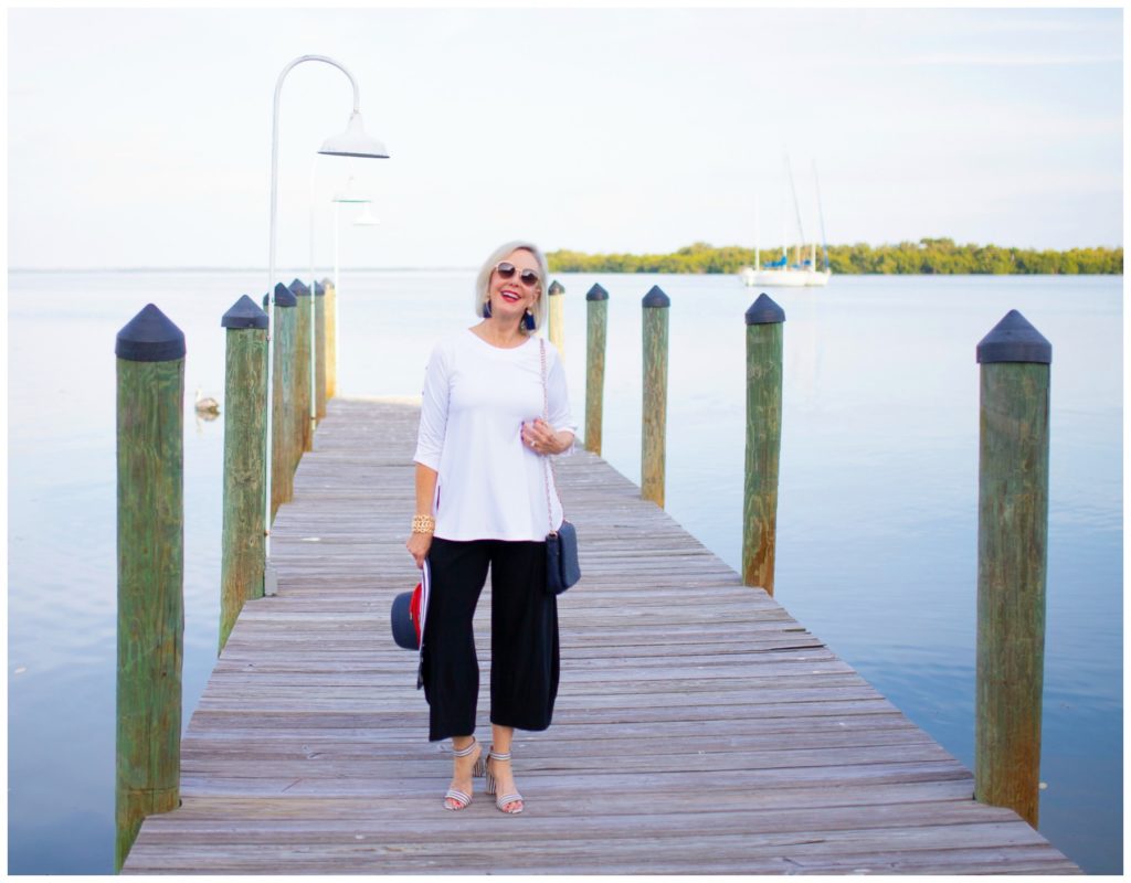 Sheree Frede of the SheSheShow standing on a pier wearing  split skirt with white tunic top