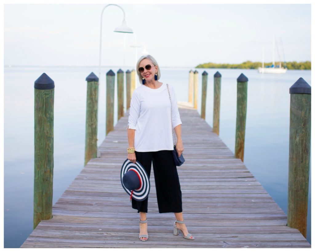 Sheree Frede of the SheSheShow standing on a pier wearing split skirt with white tunic top