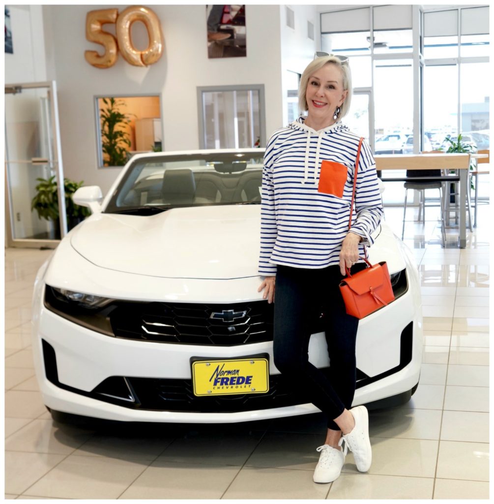 Sheree Frede standing in front of white Chevrolet wearing a white and blue stripe with orange pocket