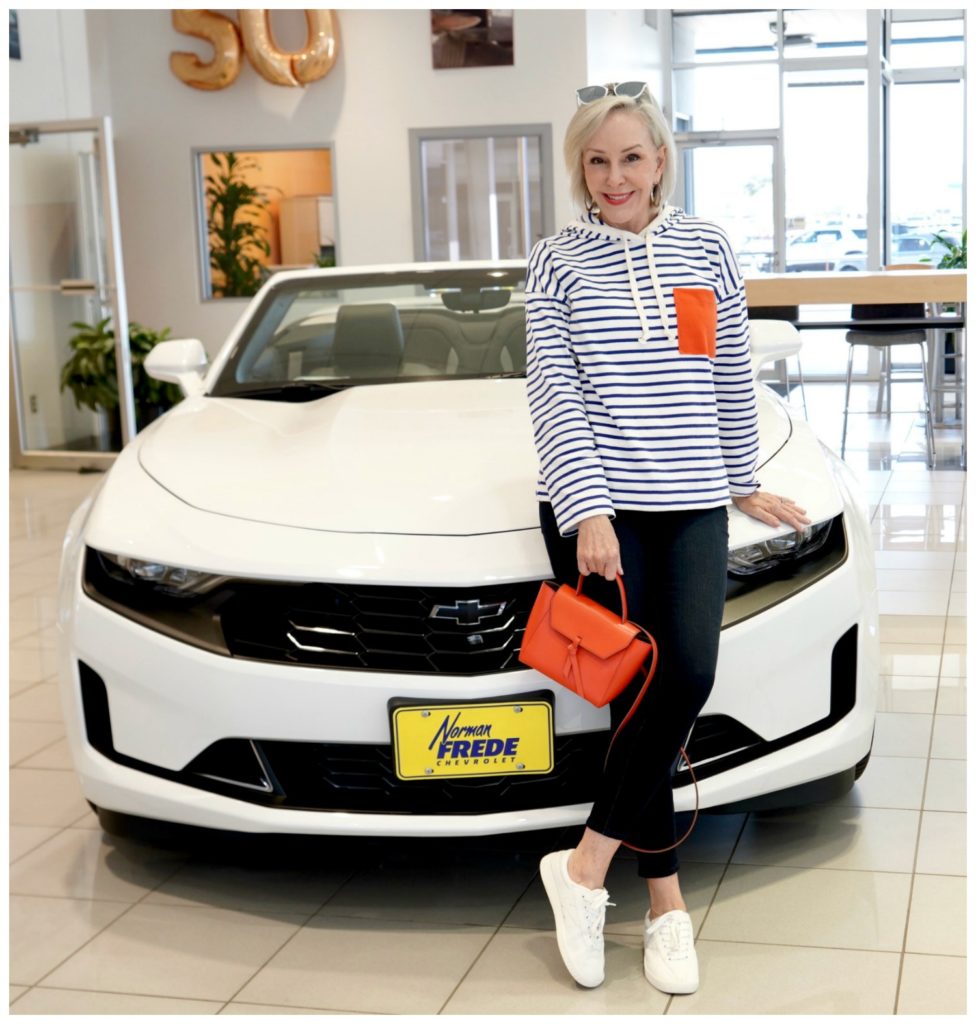 Sheree Frede standing in front of white Chevrolet wearing white and blue stripes with orange pocket